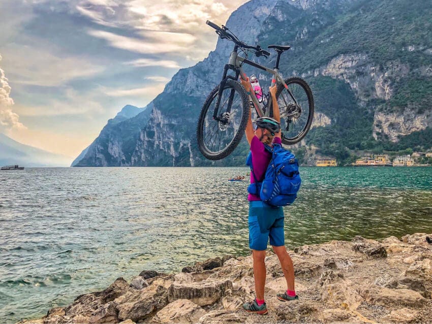 Sportliche Frau mit Fahrrad am Gardasee. das Ziel der Via Claudia Augusta.