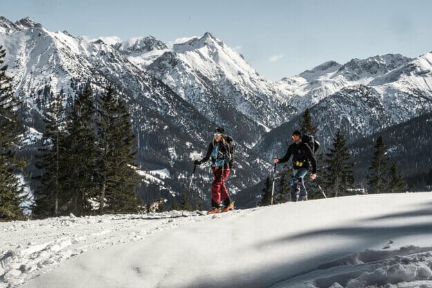Eine Frau und ein Mann beim Aufstieg zum Gipfel in den verschneiten Alpen