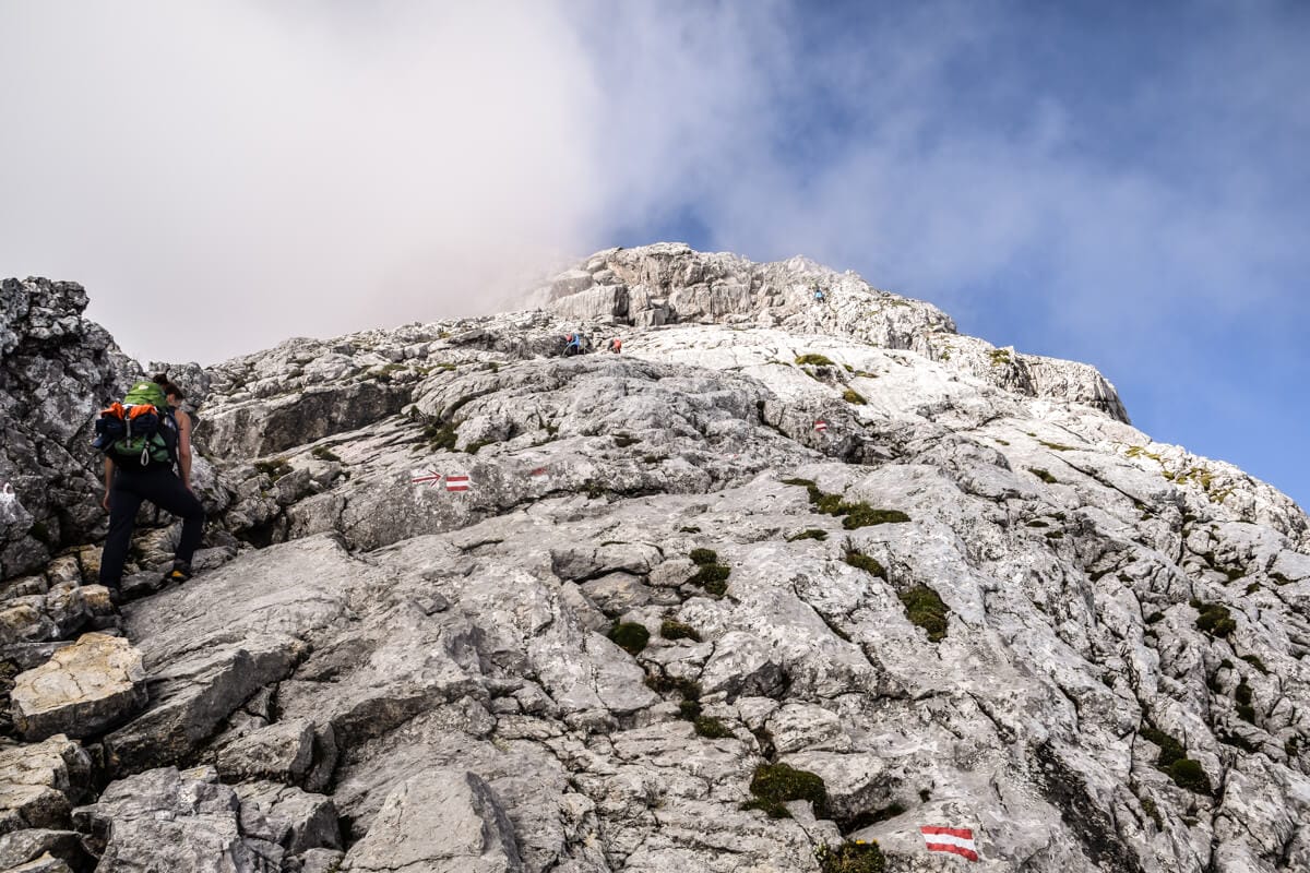 Eine Frau kämpft sich eine Felswand hoch zum Hocheck auf der Watzmanntour