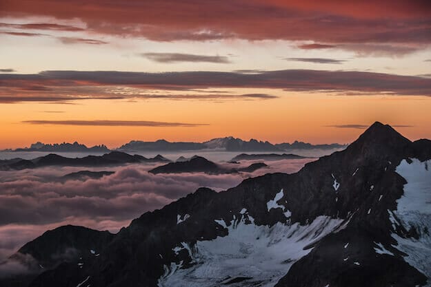 Traumhafter Sonnenuntergang an der Müllerhütte über einer Wolkendecke. Gipfel stoßen durch die Wolken.
